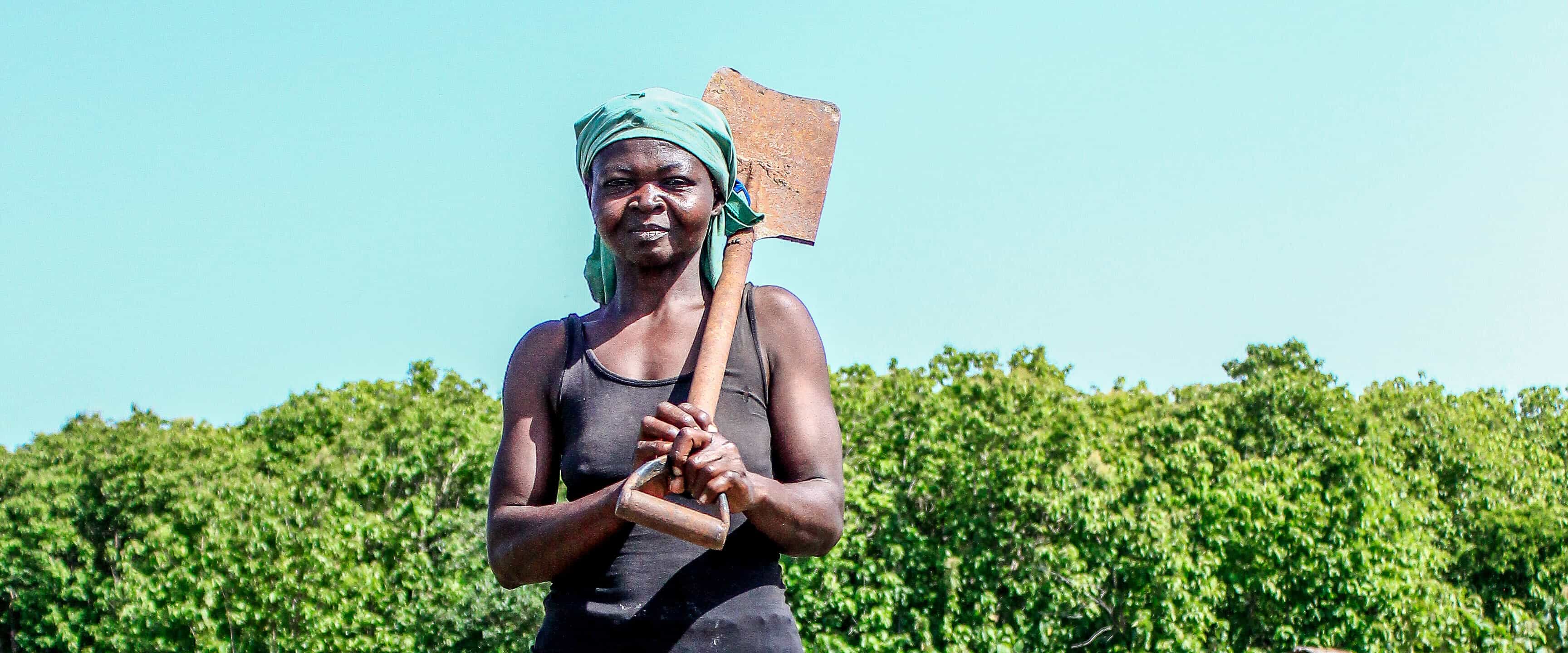 A woman holding a shovel and posing for the camera at the OKO Forestry project.