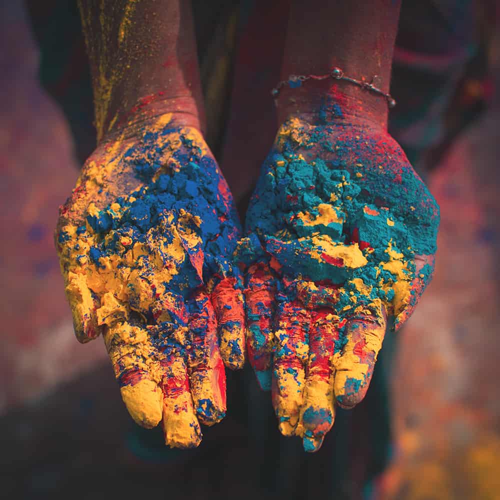 A woman's hands up-close with colored powder in them.